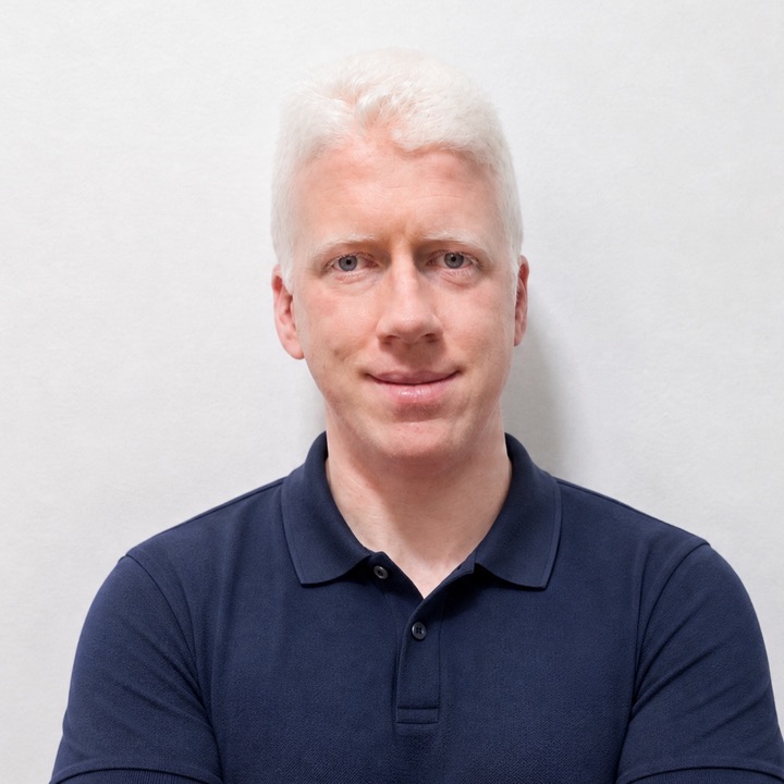 Rubén El Albino, con el pelo blanco y un polo azul marino, sonríe a cámara.